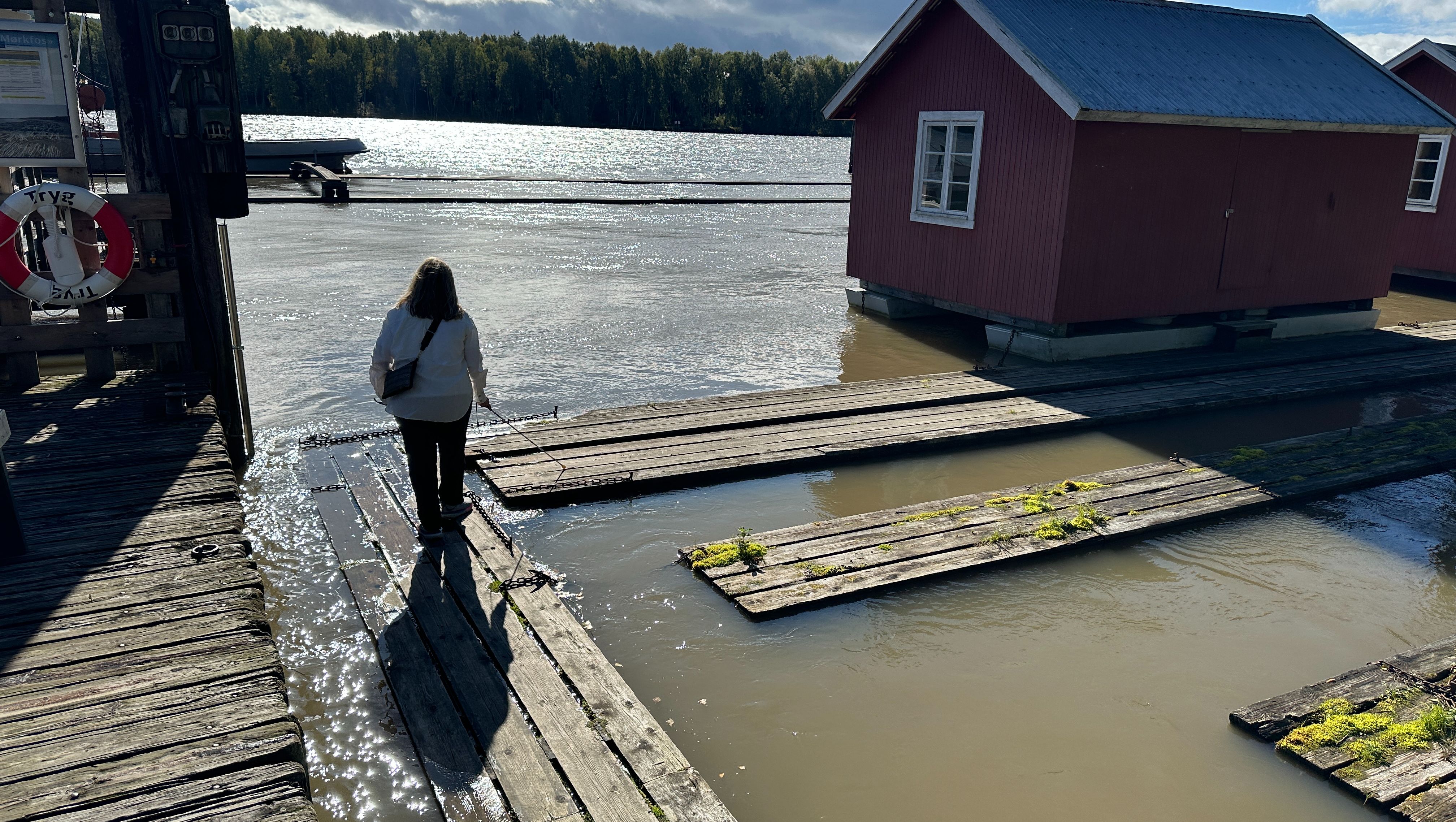 Person med hvit stokk på vei ut på trebruer i vannet i Fetsund